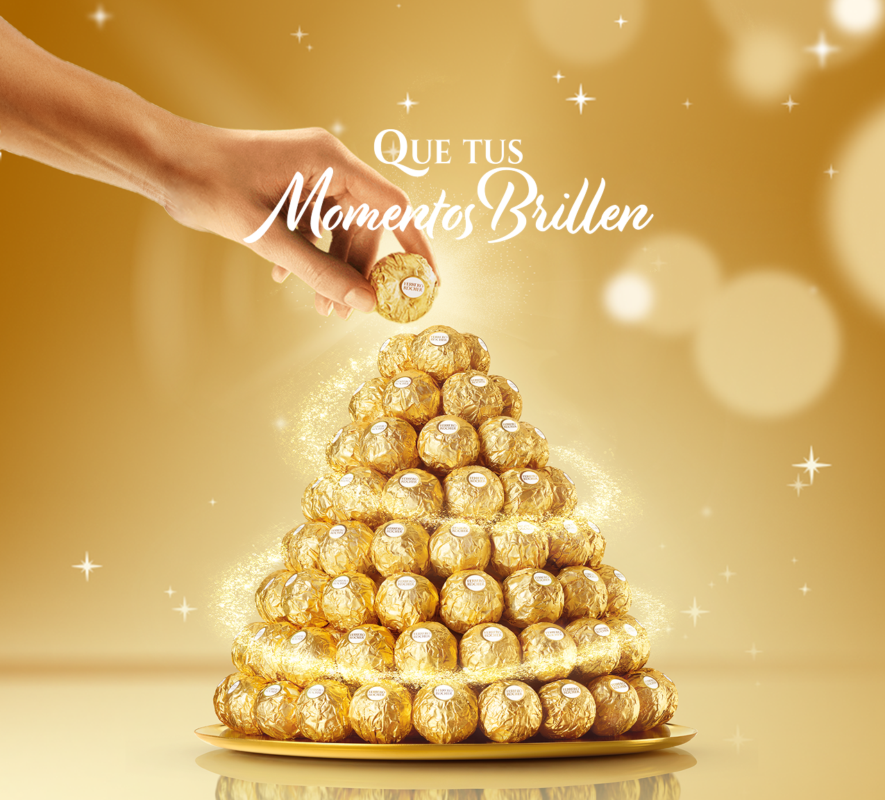 Una mano coloca un Ferrero Rocher en la cima de una pirámide de Ferrero Rocher.